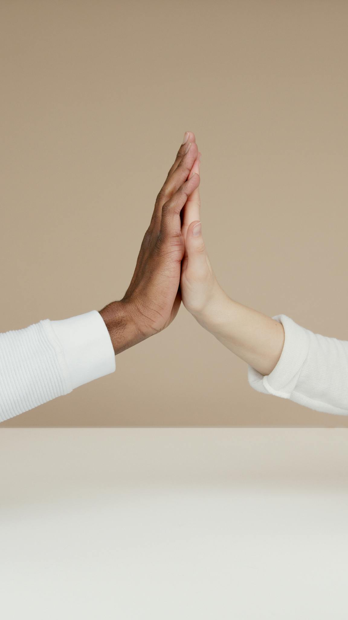 Two hands meet in a high-five, symbolizing cooperation and unity.